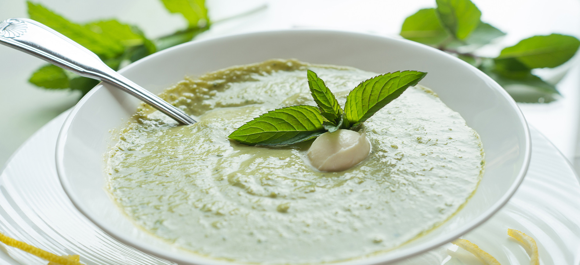 Minted pea soup with mint garnish in white bowl