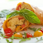 egg filled crepe with basil and cherry tomato garnish