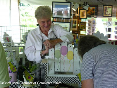 two women with painted Adirondack chair at art festival