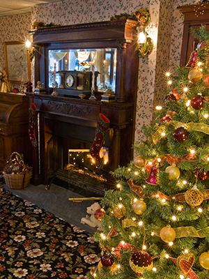 Fireplace with wood mantel & mirror, stockings hanging, Christmas tree on right