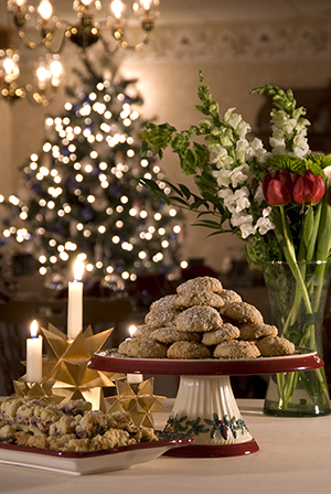 Paradise Falls cookies on cakestand, cookies on platter to left, candles, Christmas tree, vase of flowers behind