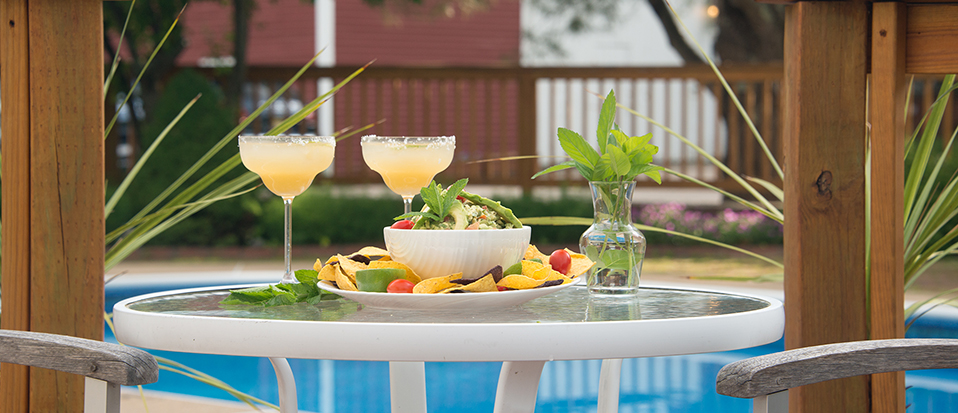 Table with drinks & snacks, pool & fence in background