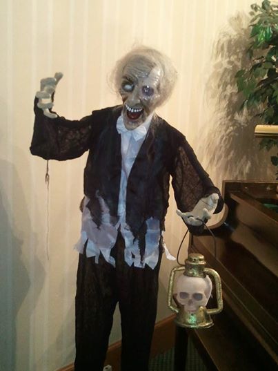 Ghoul figure with lantern by grand piano