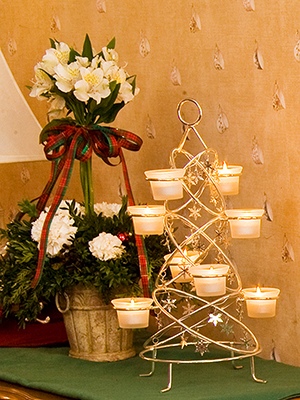 White & evergreen topiary with red & green plaid ribbon on left, silver candle tree on right